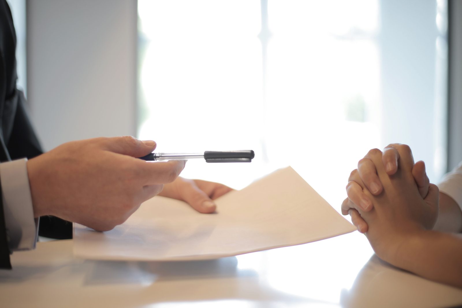 A lender handing over mortgage paperwork and a pen to sign