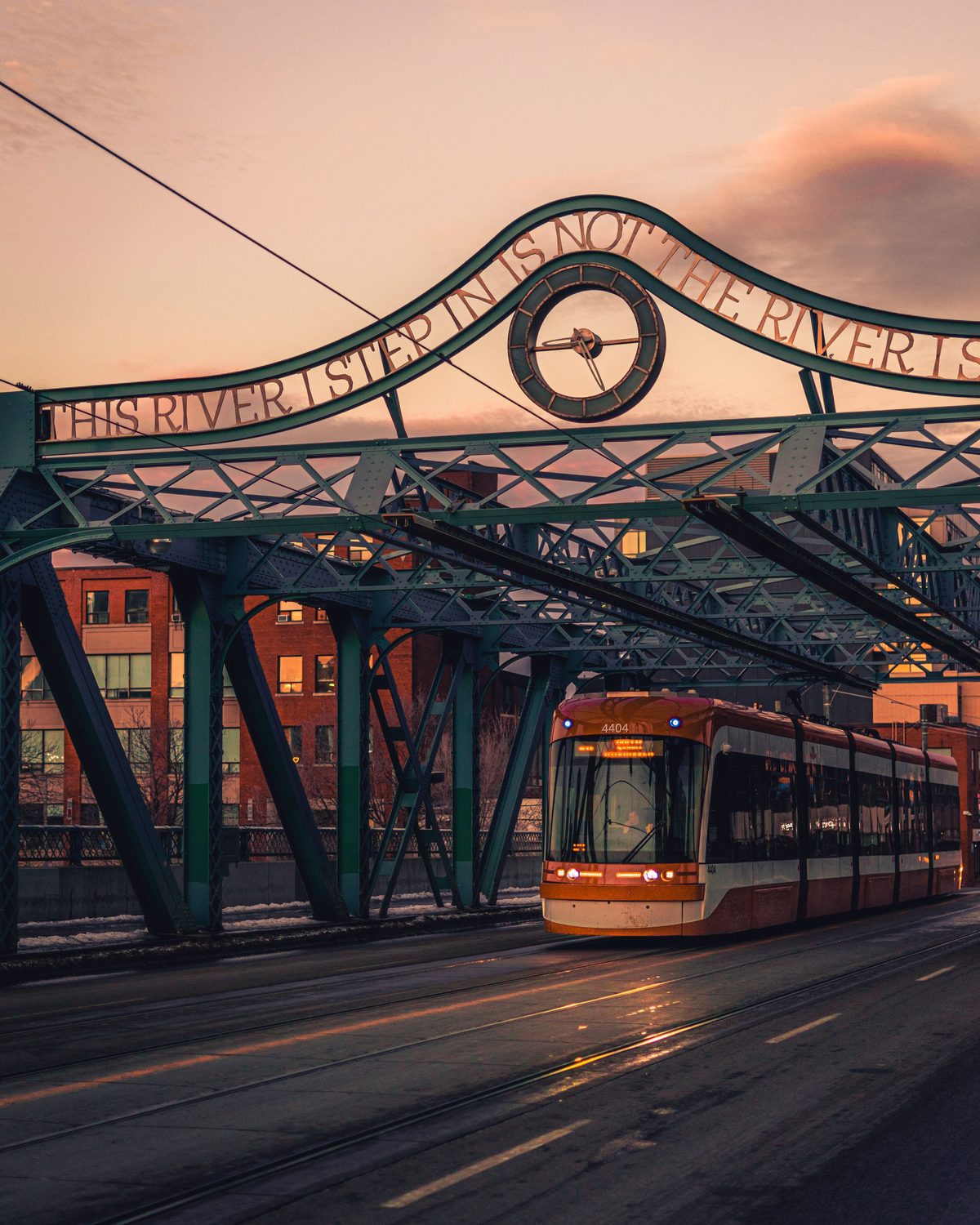A Toronto streetcar crossing a historic bridge in a city neighbourhood